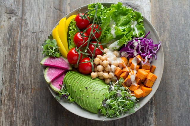 A dish full of sliced veggies, cherries, and fruits.